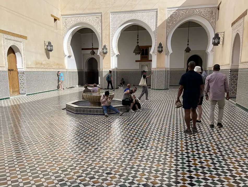 Intricate zellij tiles and marble columns inside Moulay Ismail Mausoleum in Meknes.