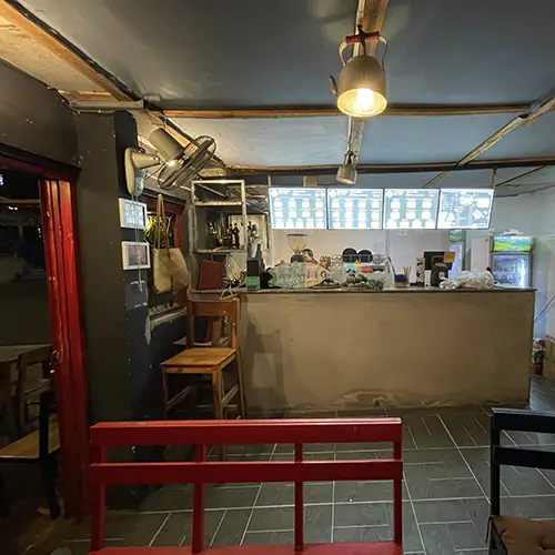 Simple indoor counter with stools and menu board at a small burger café.