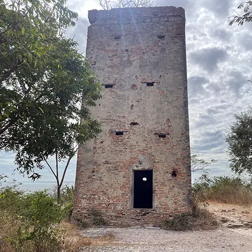 Ruined rectangular brick tower with small openings and dark doorway.