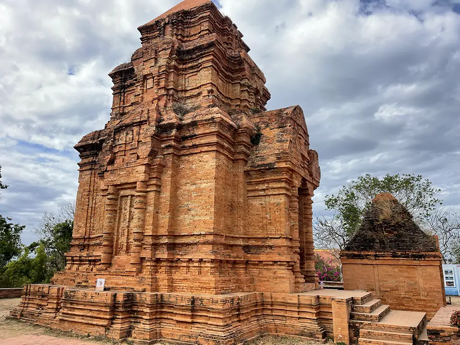 Close view of weathered brick tower corner with carved bands and niches.