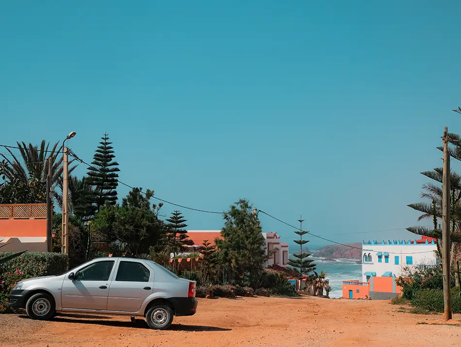 Quiet residential street with low buildings and parked car in Mirleft.