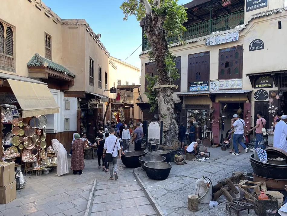 Lively blacksmith square in the medina with artisans hammering copper.