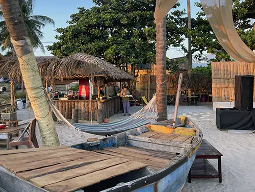 Wooden deck seating and draped fabric details inside The Current beach bar in Mui Ne.