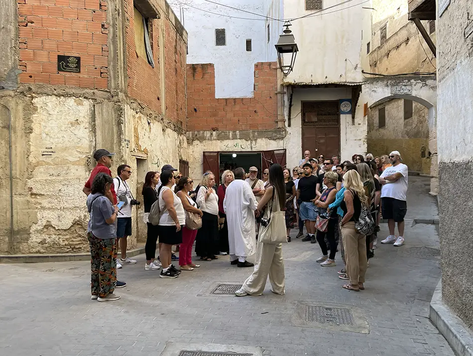 Tour group following a guide through a Fes medina street.