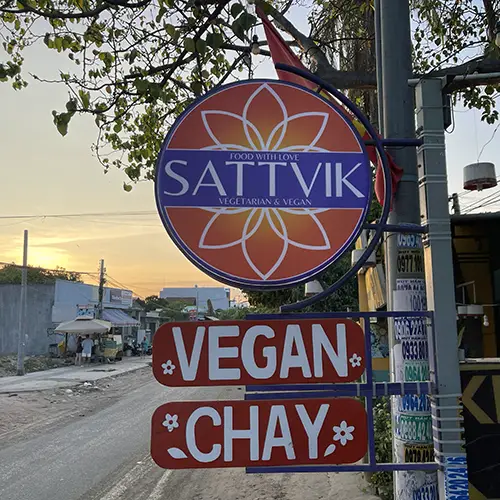 Roadside hanging sign marking vegan restaurant in Mui Ne.