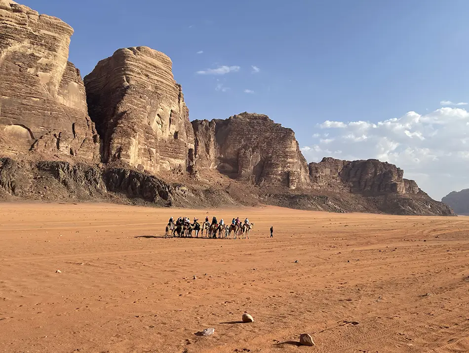 Camel caravan crossing vast red sands and sandstone cliffs in Wadi Rum, Jordan. Here The Martian was filmed