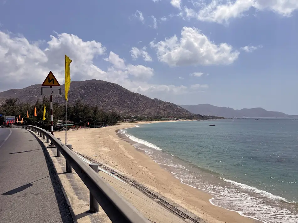 Scenic coastal road between Mui Ne and Phan Rang with beach and mountains.