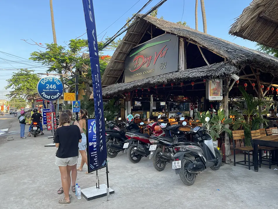 Street view of Dong Vui food court entrance with motorbikes parked outside.