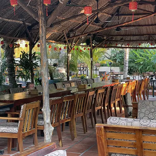 Open-air wooden seating area inside a thatched-roof dining space.