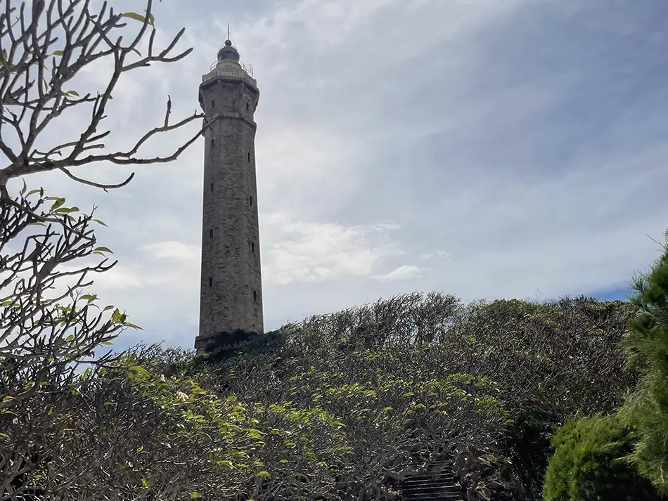 Ke Ga lighthouse standing on a rocky hill above coastal vegetation.