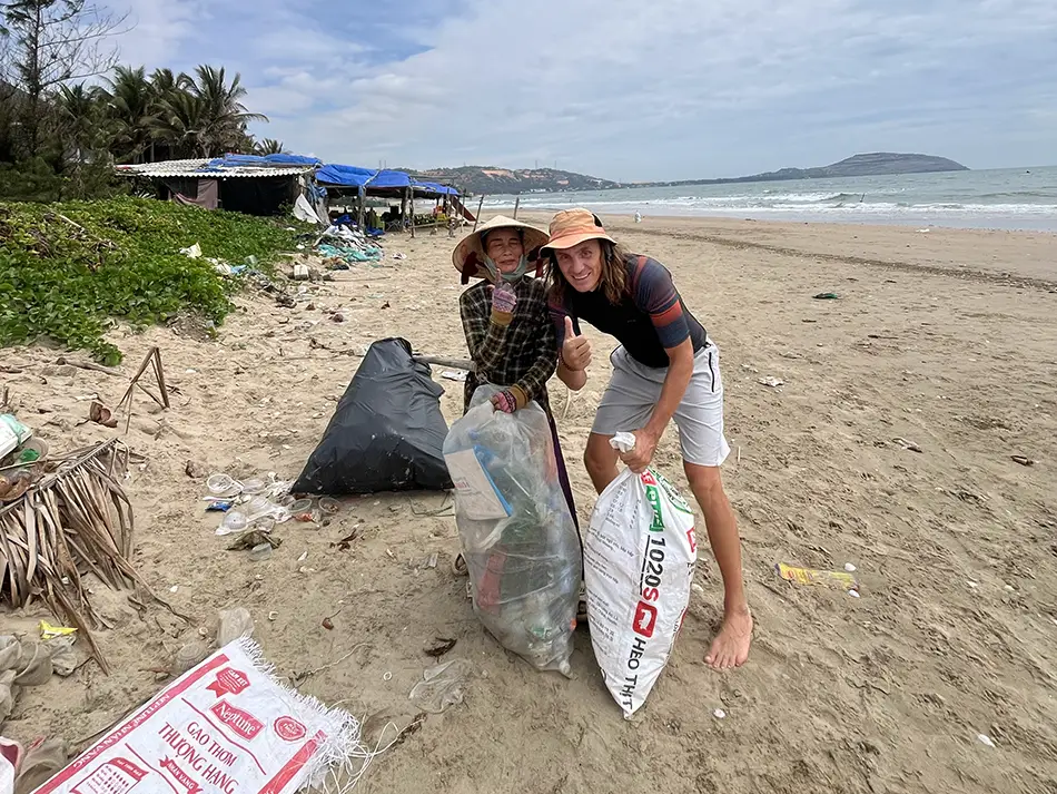 A traveler cleaning trash on Mui Ne beach, showing pollution reality