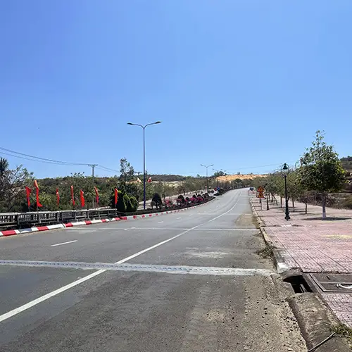 Wide highway near Mui Ne with smooth asphalt and sidewalk under clear blue sky.