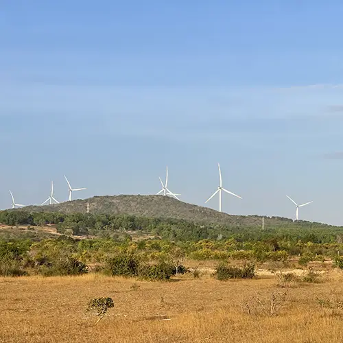 Wind turbines on dry hills visible from the highway near Mui Ne.