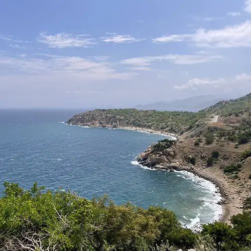 Curving coastline with cliffs and blue sea along the Mui Ne to Phan Rang road.