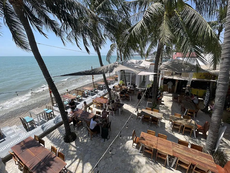 Open-air seaside restaurant terrace in Mui Ne with palm trees and ocean view.