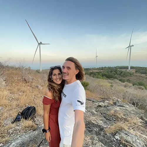 Travelers posing together on a rocky hilltop with multiple wind turbines