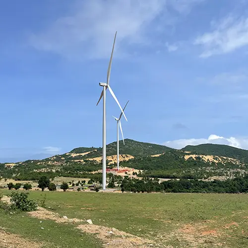 Large wind turbines standing on green hills near Mui Ne.