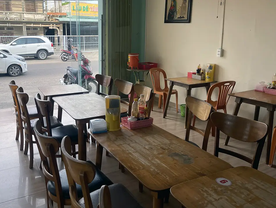 Bright dining room of an authentic vegetarian cafe in Mui Ne with wooden tables.