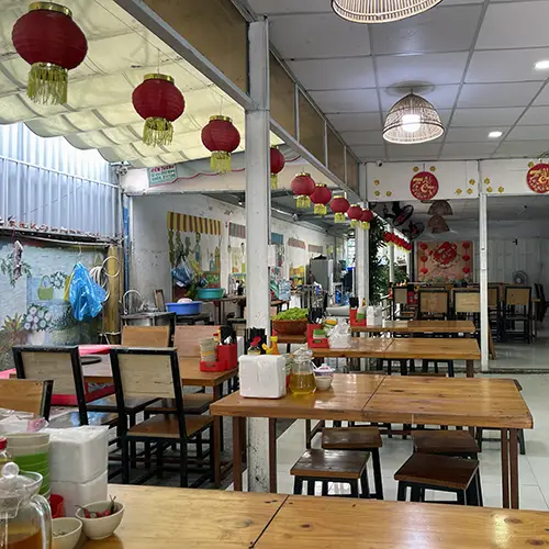 Interior of a local bánh khọt restaurant with tables, diners, and traditional decor