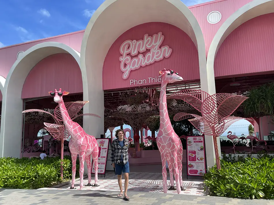 Entrance to Pinky Garden attraction at Bikini Beach featuring pink arched facade, decorative pink giraffes and visitors at the door