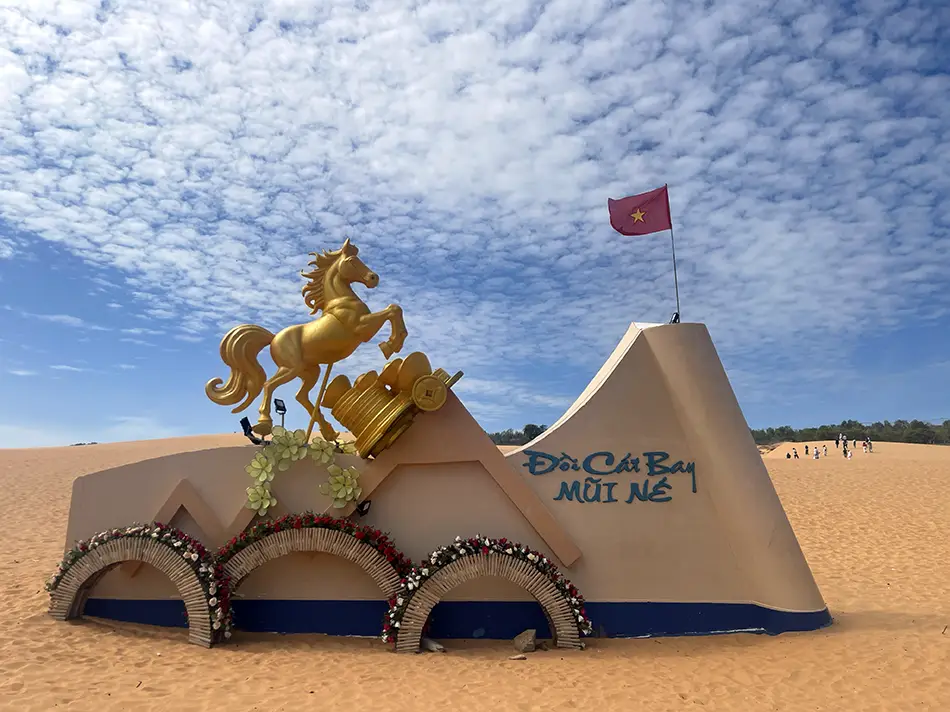 Decorative horse sculpture and painted sign at the entrance to the red sand dunes area, with dunes