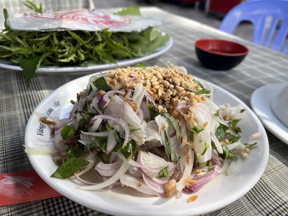Gỏi cá mai set with cured white fish, fresh herbs, and rice paper wrappers arranged on a table