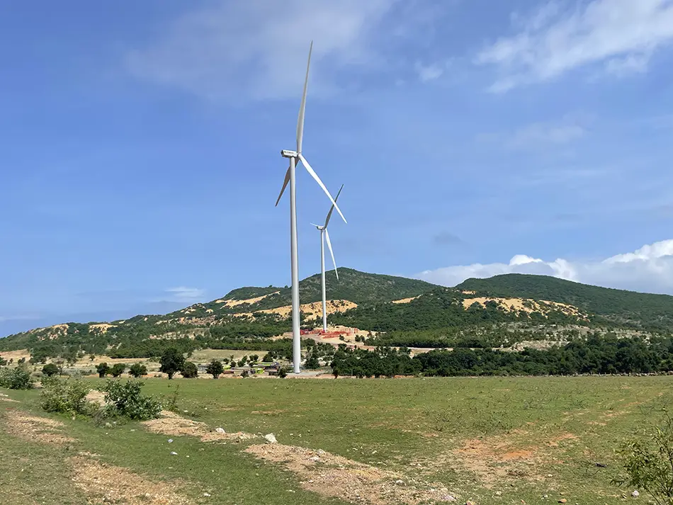 Lush green hills dotted with wind turbines along the scenic coastal road between Mui Ne and the sand dunes