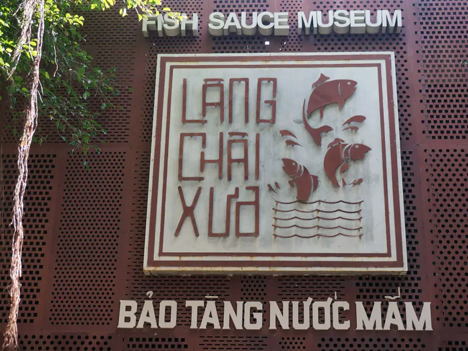 Entrance sign of Lang Chai Xua Fish Sauce Museum — "Bảo Tàng Nước Mắm" — mounted on a dark brick wall, one of Mui Ne's hidden gems for cultural tourism