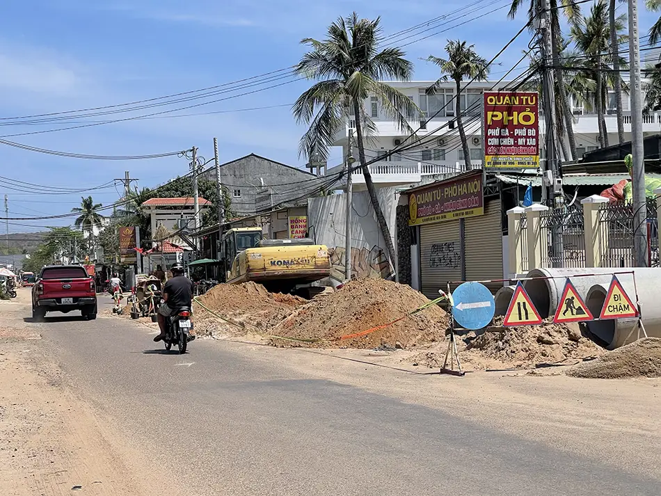 A section of Nguyen Dinh Chieu Street with small shops, plastic chairs, and construction materials along the roadside — a typical scene along the main tourist strip