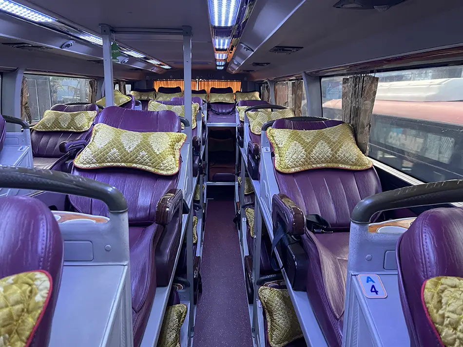 Interior of a Vietnamese sleeper bus showing rows of purple reclining berths stacked in two tiers with a narrow aisle between them