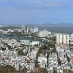 Aerial view of Vung Tau city with coastline, buildings, and green hills in the background