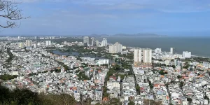 Aerial view of Vung Tau city with coastline, buildings, and green hills in the background