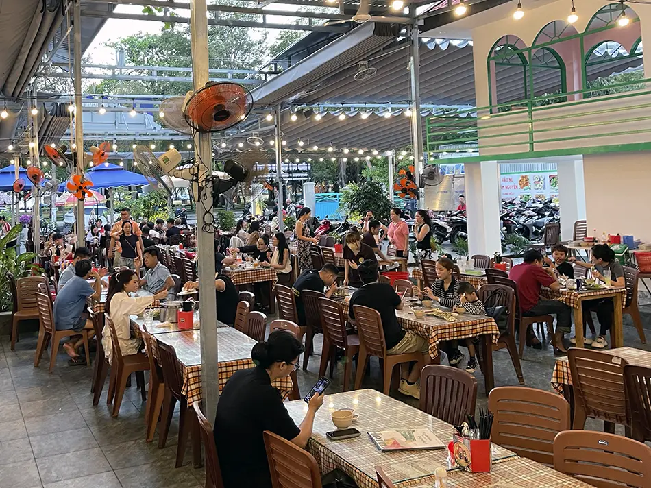 Crowded open-air seafood restaurant at sunset with many diners at tables, showing the busy evening atmosphere
