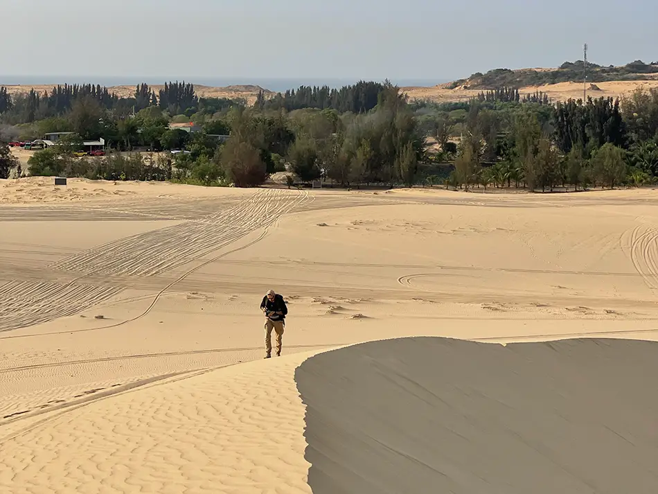 A lone figure walking across vast white sand dunes — one of the top stops on a budget Mui Ne jeep tour