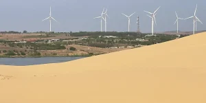 Row of wind turbines on green hills seen from the White Sand Dunes Mui Ne