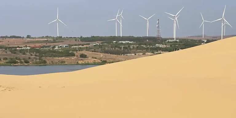 Row of wind turbines on green hills seen from the White Sand Dunes Mui Ne