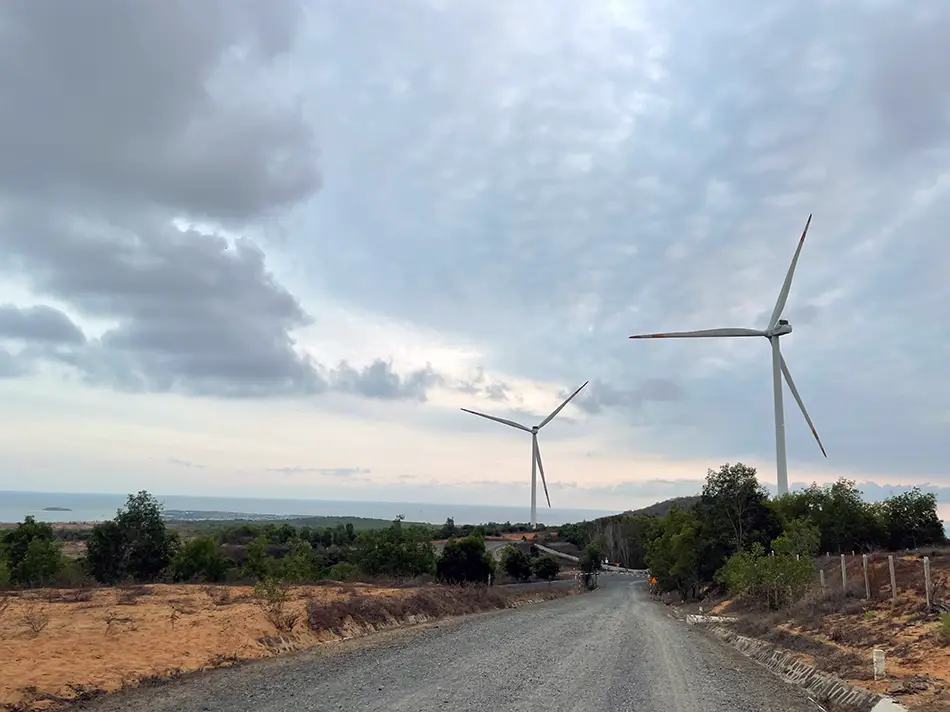 Two large wind turbines lining a straight rural road province near Mui Ne, an off-the-beaten-path viewpoint