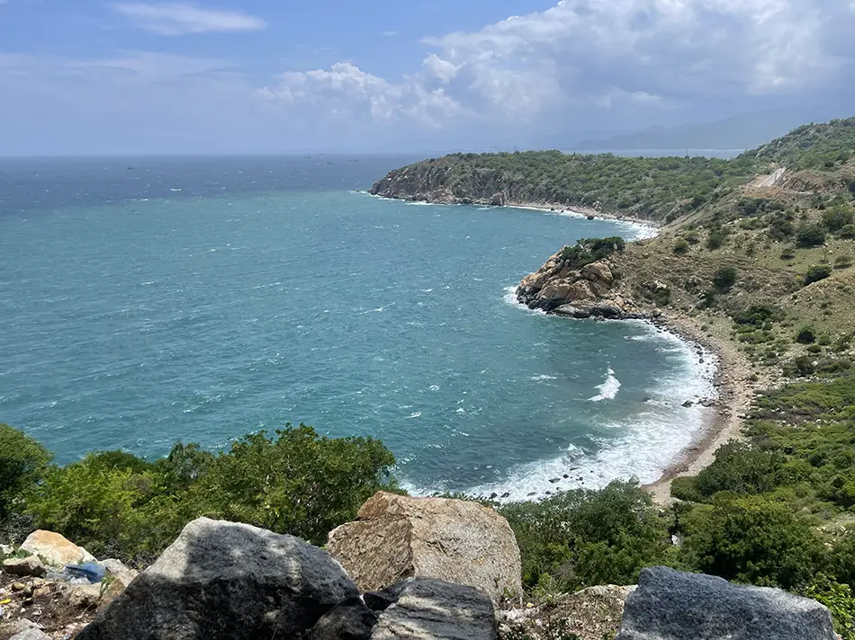 Elevated view from the road looking down at a coastal bay with clear blue water.