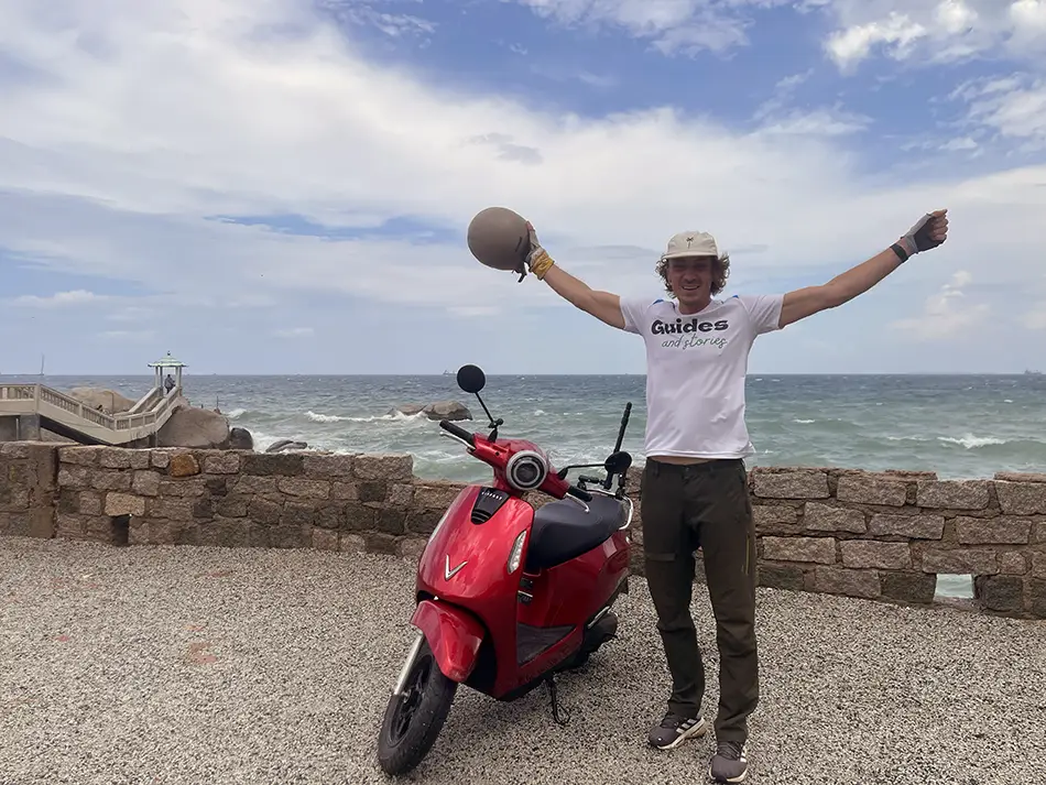Yuri Malykh riding an electric scooter along a coastal road in Vietnam during a day of his journey.