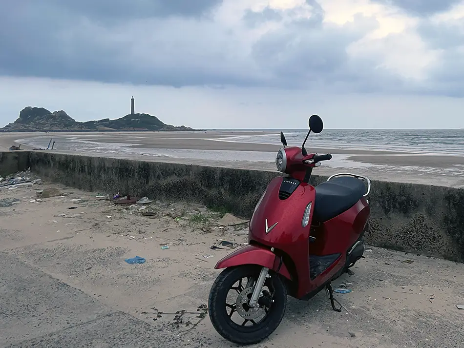 Vinfast Electric scooter parked with Ke Ga lighthouse at the background
