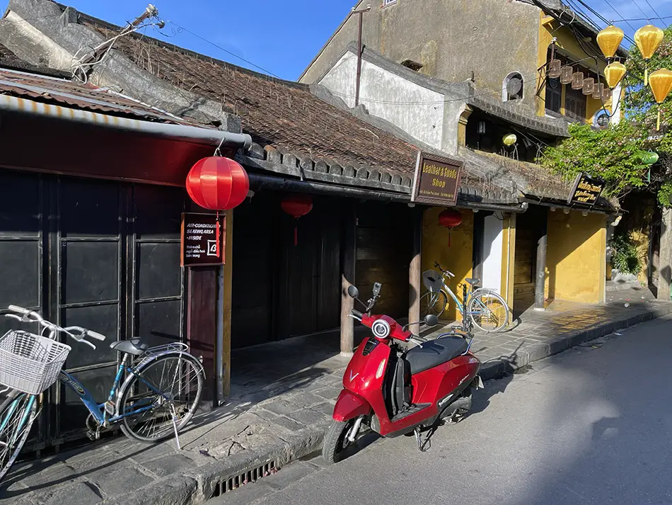 A bright red eco-friendly electric scooter parked on a street in the ancient town of Hoi An.