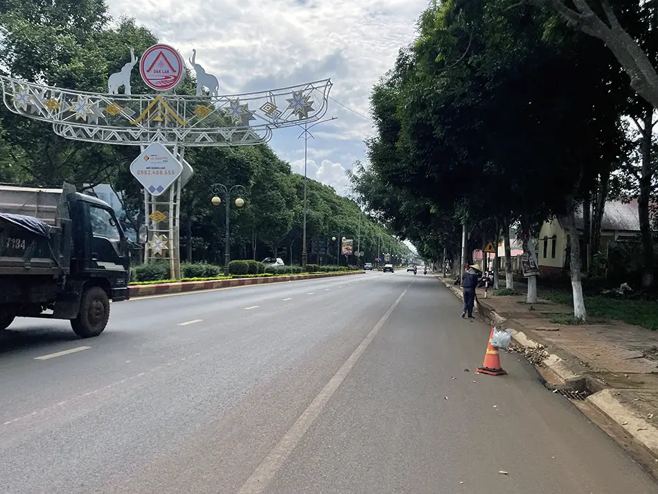 First-person view riding on a highway alongside trucks near Buon Ma Thuot.