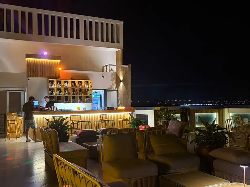 Mana Beach Hotel rooftop bar at dusk with empty lounge seating overlooking the dark sea