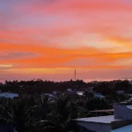 Orange and pink sunset over Mui Ne rooftops seen from a hillside viewpoint above town