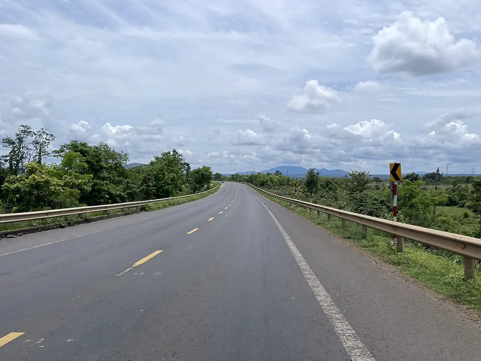 A smooth two-lane highway in Vietnam lined with trees on both sides.