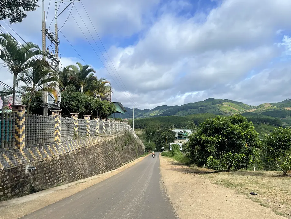 A rural road in Vietnam descending toward the foothills of green rolling hills.