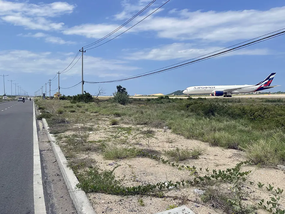 A road running right alongside an airport with an airplane in the background.