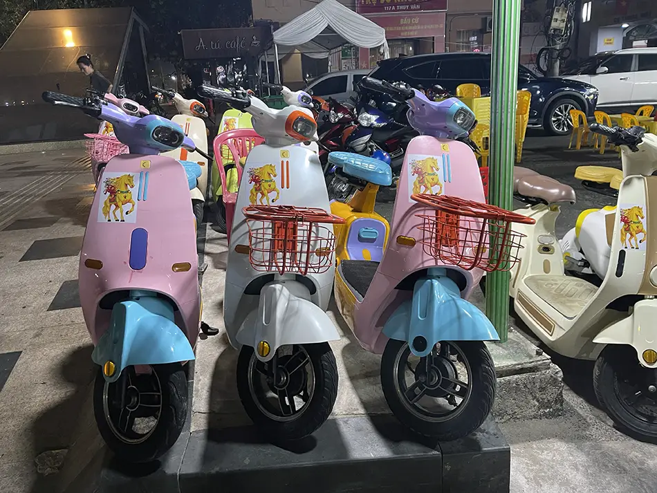 A row of colorful rental electric scooters in pink, white, and teal parked side by side — hiring an e-scooter is one of the top Vung Tau travel tips for getting around independently on a budget