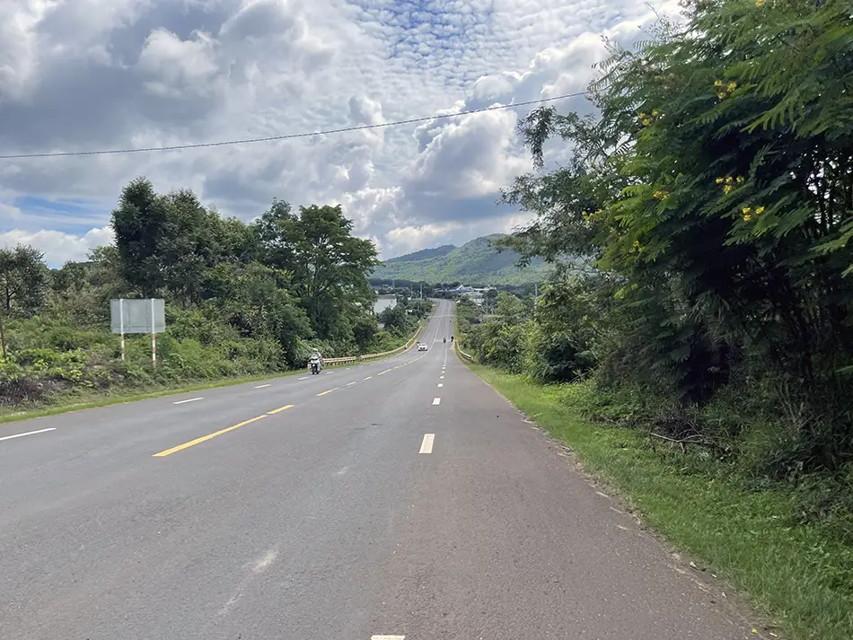 A scenic road in the Central Highlands of Vietnam descending into a lush green valley.