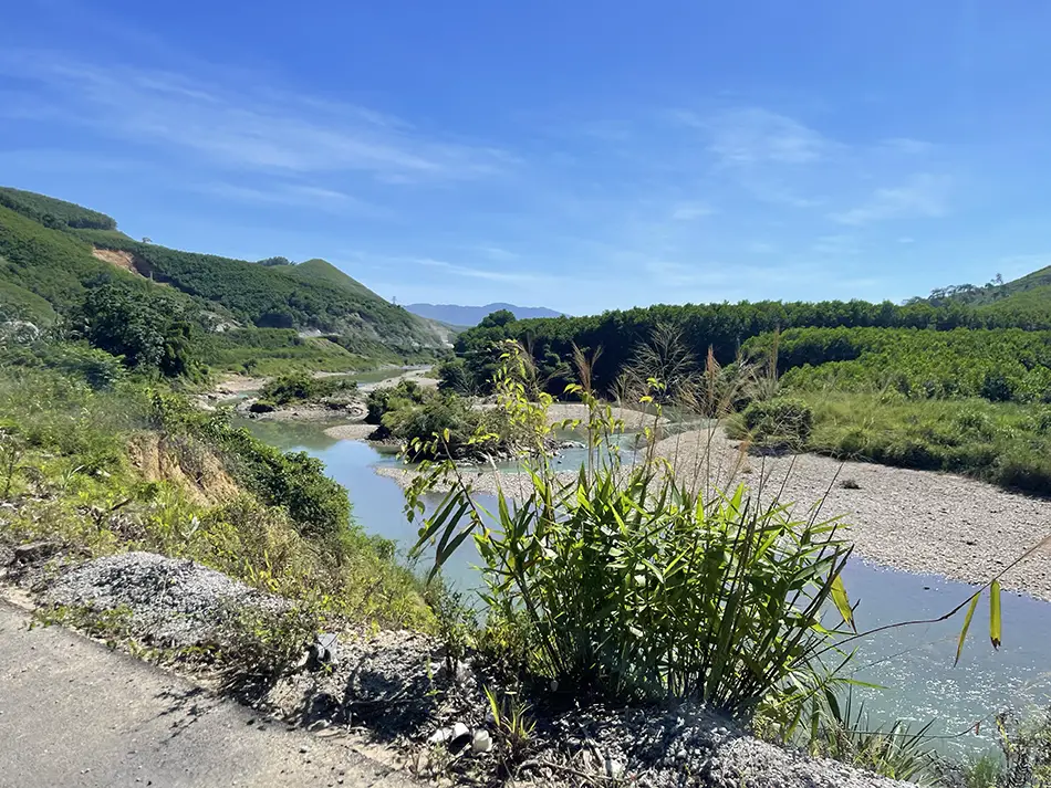 View of a river flowing alongside a scenic road in Vietnam.